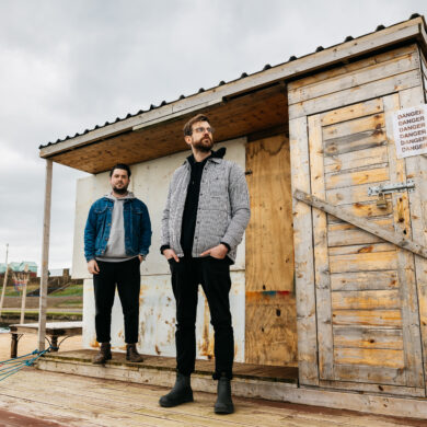 The band duo JOHN standing in front of a shed
