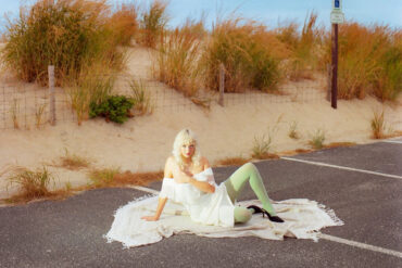girlpuppy sitting on the floor in a car parking space by the beach
