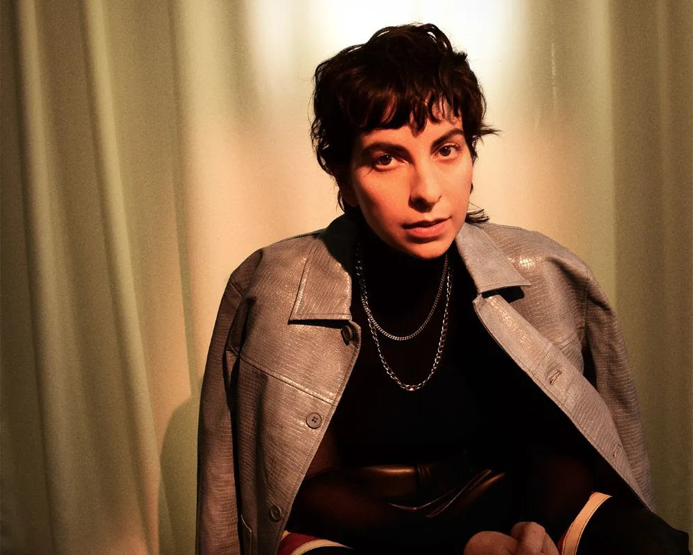 IN CONVERSATION: Becca Mancari "the music reflects the emotions that I feel inside, which can be chaotic, sad, hopeful, spiritual, lonely, and strong" 22 Photo of Becca Mancari looking at the camera with a coat over their shoulders