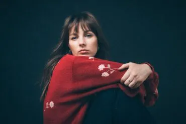 IN CONVERSATION: Gena Rose Bruce "I'm always pretty anxious before a show so I can't really eat or drink anything but I would appreciate having fresh flowers in the room" 25 Gena Rose Bruce in a red top looking over her shoulder into the camera.