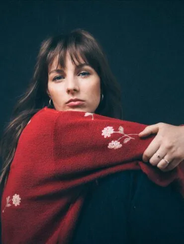 IN CONVERSATION: Gena Rose Bruce "I'm always pretty anxious before a show so I can't really eat or drink anything but I would appreciate having fresh flowers in the room" 23 Gena Rose Bruce in a red top looking over her shoulder into the camera.