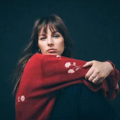 Gena Rose Bruce in a red top looking over her shoulder into the camera.