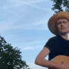 Alex Sebley from Pregoblin wearing a straw hat and holding a guitar.